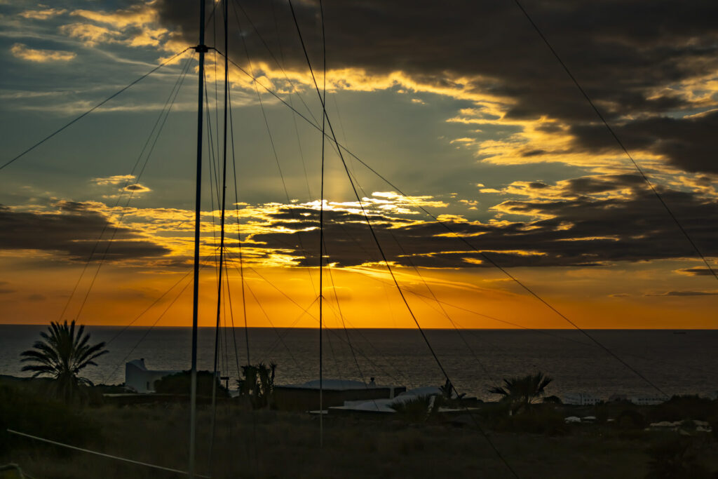 Sunset over the sea behind the vertical antennas